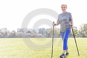 Active senior woman with trekking poles walking in park