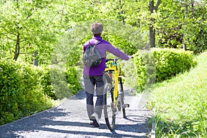 Active senior woman using a bike in summer park