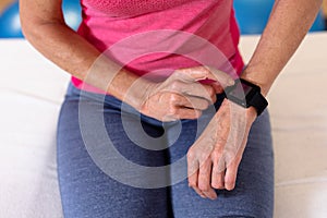 Active senior woman using smartwatch in sports center