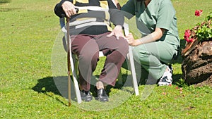 Active seniors concept. Elderly woman seated in the garden talking to asian nurse