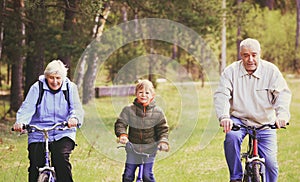 Active seniors with grandson riding bikes in nature