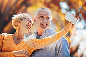 Seniors taking selfies of them having fun outside in the autumn forest