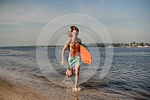 Active beach lifeguard running along the river bank with li