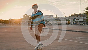 Active skateboarder making trick on board at street. Curly man rolling asphalt