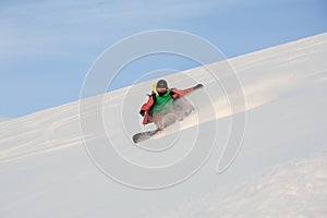 Active snowboarder riding down the snowy slope