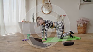 Active sporty fit woman practicing yoga online class, doing clamshell exercise indoors