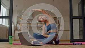 Active sporty fitness black woman practicing seated side bend stretch indoors