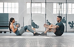 Active, sporty fitness couple or gym partners training together, doing core exercises with heavy equipment. Male trainer
