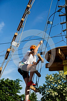 Active sporty kid in helmet doing activity in adventure park with all climbing equipment. Active children climb on the trees