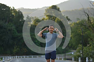 Active sporty man listening to music through headphones while running in the morning