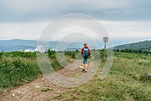 Active sporty man trekking on peak of Jeseniky mountains,Czech Republic.Backpacker enjoying view of foggy mountain.Wanderlust