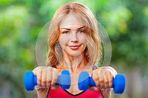 Active sporty woman doing morning exercises with dumbbells at home