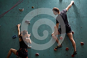 Active sporty woman and man practicing rock climbing on artificial rock