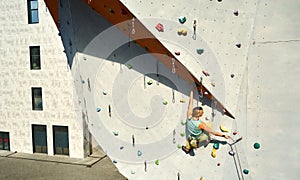 Active sporty woman practicing rock climbing on artificial rock wall in climbing gym. reaching holds, making hard move