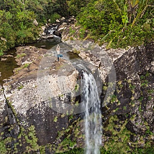 Active sporty woman relaxing in nature, practicing yoga on high clif by 500 feet waterfall at Black river gorges