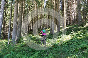 Active sporty woman riding mountain bike on forest trail .