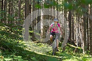 Active sporty woman riding mountain bike on forest trail .