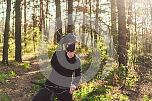 Active sporty woman riding mountain bike on forest trail, wearing a face mask against air pollution and coronavirus.