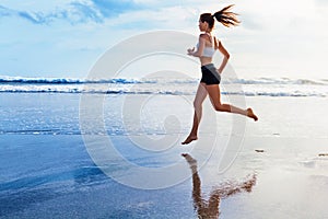 Active sporty woman run along sunset ocean beach. Sports background.