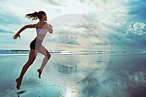 Active sporty woman run along sunset ocean beach. Sports background.