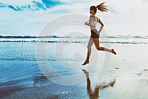 Active sporty woman run along sunset ocean beach. Sports background.