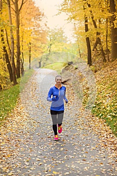 Active and sporty woman runner in autumn nature