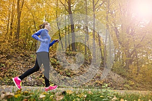 Active and sporty woman runner in autumn nature