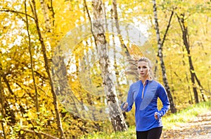 Active and sporty woman runner in autumn nature