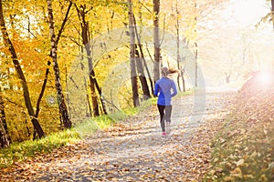 Active and sporty woman runner in autumn nature