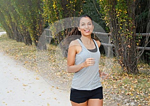 Active sporty young runner woman running in the park. Smiling runner athlete training outdoors