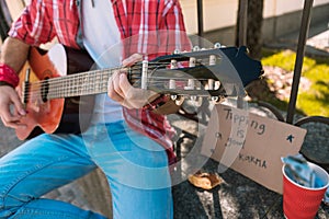 Active street musician changing music with guitar