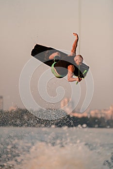 active strong man jumping and flips on wakeboard over splashing wave