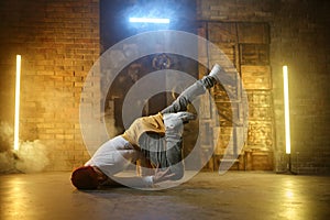 Active stylish guy hip hop dancer training or performing over loft studio