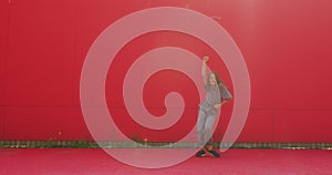 Active teen girl cool dancing having fun outdoors on red wall background. Young female dancer perform contemporary dance