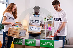 Active teenagers separating paper from plastic while sorting waste