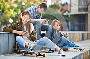 Active teens playing on smarthphones and listening to music