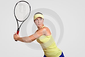 Active tennis player dressed in court cap, t shirt and shorts, holds racket, prepares for competiton, wants to win match, stands a