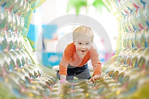 Active toddler boy having fun on inflatable attraction in entertaining center. Funny child is playing on indoor playground. Kids