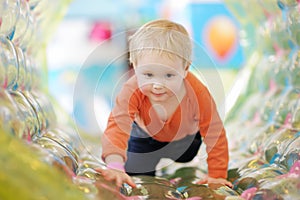 Active toddler boy having fun on inflatable attraction in entertaining center. Funny child is playing on indoor playground. Kids