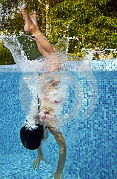 Active underwater child jumps to swimming pool