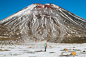 Active volcanic mountain Mt. Ngauruhoe and adventurous mountain hiker back view with backpack, Tongariro crossing
