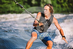 Active wakesurfer jumping on wake board down the river waves. Surfer on wave. Male athlete training on wakesurf training photo