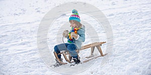 Active winter outdoors games for kids. Happy Christmas vacation concept. Boy enjoying winter, playing with sleigh ride