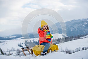 Active winter outdoors games for kids. Happy Christmas vacation concept. Boy enjoying winter, playing with sleigh ride