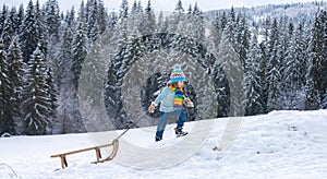 Active winter outdoors games for kids. Happy Christmas vacation concept. Boy enjoying winter, playing with sleigh ride