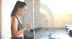 Active woman athlete taking rest and use smartphone after exercising at gym. Fitness Healthy lifestye and workout at gym concept photo