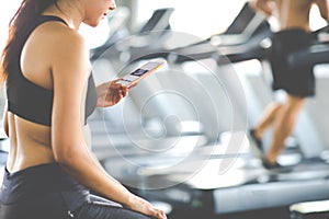 Active woman athlete taking rest and use smartphone after exercising at gym. Fitness Healthy lifestye and workout at gym concept photo