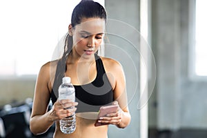 Active woman athlete taking rest and use smartphone after exercising at gym. Fitness Healthy lifestye and workout at gym concept photo