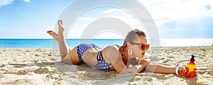 Active woman in beachwear on seacoast with sun block laying