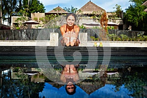 Active woman in bikini stretching at poolside to keep fit